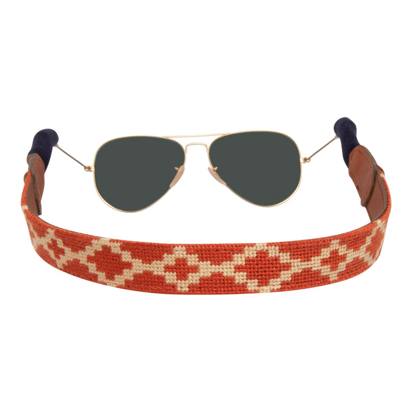 Argentine Needlepoint Sunglass Strap showing an Argentinean themed gaucho pattern in burnt orange and light tan. Sunglass straps have a full grain leather backing and secure cotton wrapped earpiece connectors for a secure grip.