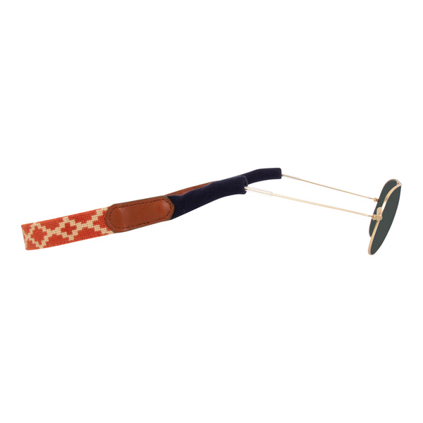 Argentine Needlepoint Sunglass Strap showing an Argentinean themed gaucho pattern in burnt orange and light tan. Sunglass straps have a full grain leather backing and secure cotton wrapped earpiece connectors for a secure grip.