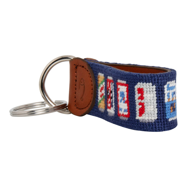 Hand-stitched Beer Can needlepoint keychain showing popular beer can pattern on both sides against a navy blue background and leather backing.  Stainless steel D-ring and keyring.