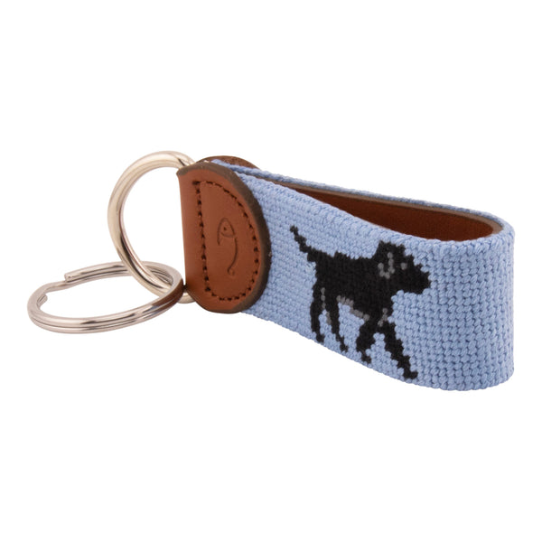 Hand-stitched black Labrador needlepoint keychain showing a black lab on both sides against a light blue background and leather backing.  Stainless steel D-ring and keyring.