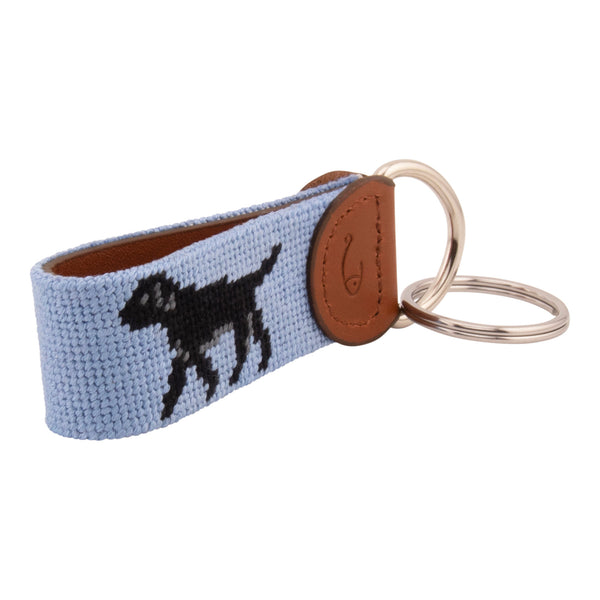 Hand-stitched black Labrador needlepoint keychain showing a black lab on both sides against a light blue background and leather backing.  Stainless steel D-ring and keyring.