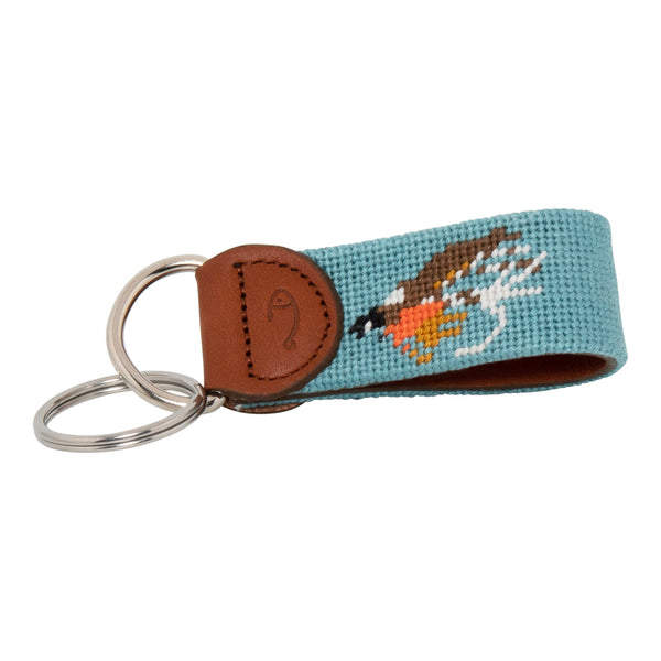 Hand-stitched Fly Fishing needlepoint keychain showing a fly fishing trout fly pattern on both sides against a light blue background and leather backing.  Stainless steel D-ring and keyring.