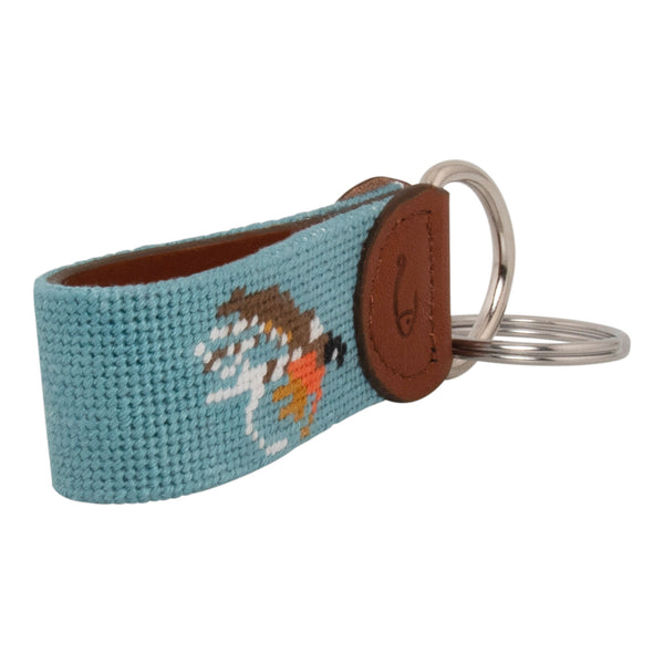 Hand-stitched Fly Fishing needlepoint keychain showing a fly fishing trout fly pattern on both sides against a light blue background and leather backing.  Stainless steel D-ring and keyring.