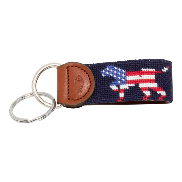 Hand-stitched Patriotic Dog needlepoint keychain showing an American Flag colored dog on both sides against a navy blue background and leather backing.  Stainless steel D-ring and keyring.