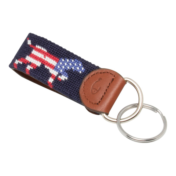 Hand-stitched Patriotic Dog needlepoint keychain showing an American Flag colored dog on both sides against a navy blue background and leather backing.  Stainless steel D-ring and keyring.