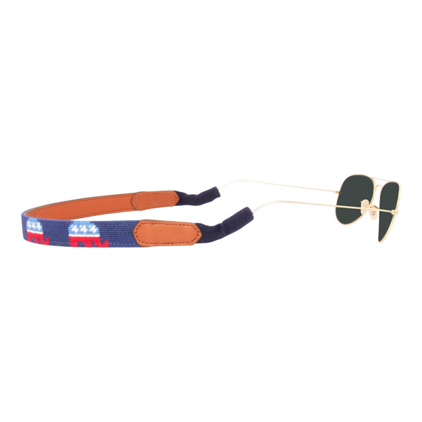 Side view republican needlepoint sunglass strap showing a republican elephant against a navy blue background with sturdy cotton covered silicone ear connectors and a soft leather backing