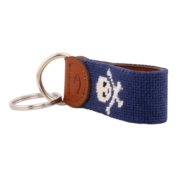 needlepoint key fob with white jolly rogers skull and crossbones against a dark navy blue background, same image on both sides, hand-stitched, leather backing, stainless steel keyring