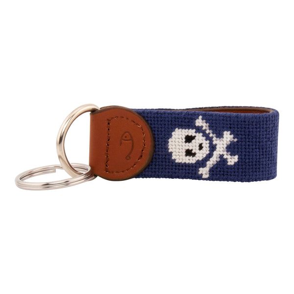 needlepoint key fob with white jolly rogers skull and crossbones against a dark navy blue background, same image on both sides, hand-stitched, leather backing, stainless steel keyring