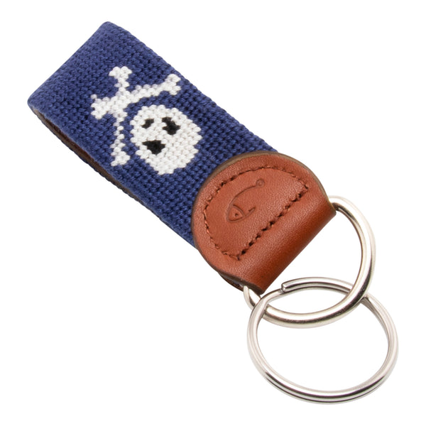 needlepoint key fob with white jolly rogers skull and crossbones against a dark navy blue background, same image on both sides, hand-stitched, leather backing, stainless steel keyring