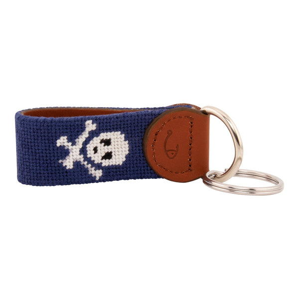 needlepoint key fob with white jolly rogers skull and crossbones against a dark navy blue background, same image on both sides, hand-stitched, leather backing, stainless steel keyring