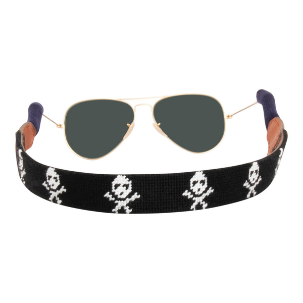 back view jolly roger needlepoint sunglass strap showing white skull and crossbones pattern against a black background with sturdy cotton covered silicone ear connectors and a soft leather backing